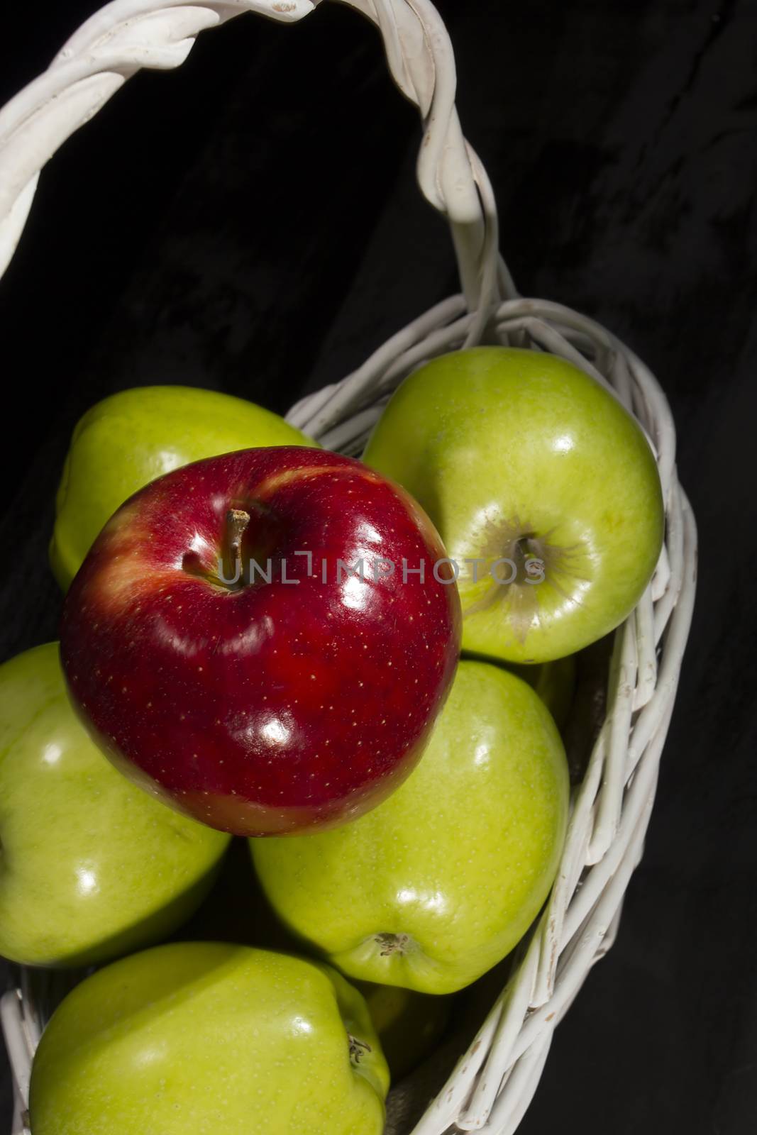 Ripe apples in a wicker basket on a black background