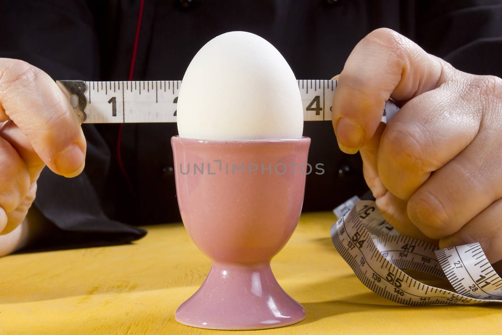 Egg in holder and hands with tape measure by VIPDesignUSA