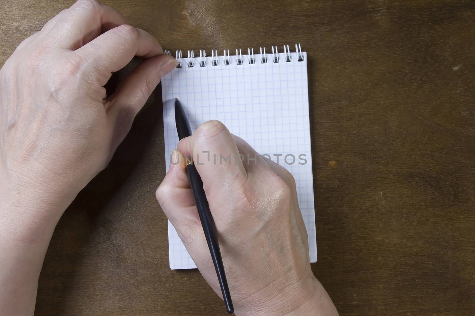 Hand writing on empty notepad on a wooden table
