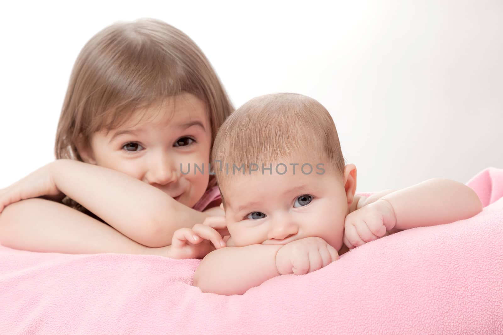 two little girls of the sisters lie on a pink plaid