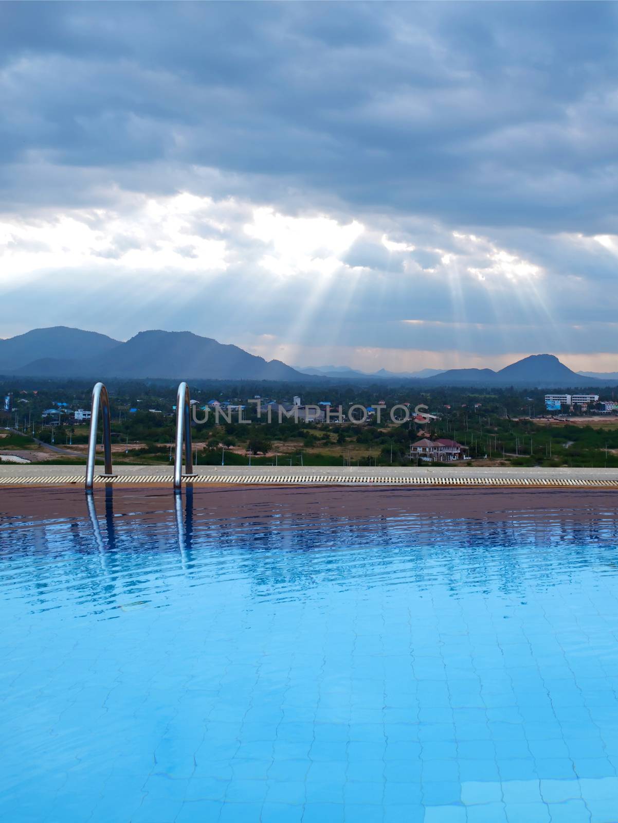 Outdoor swimming pool with sunbeam over mountains