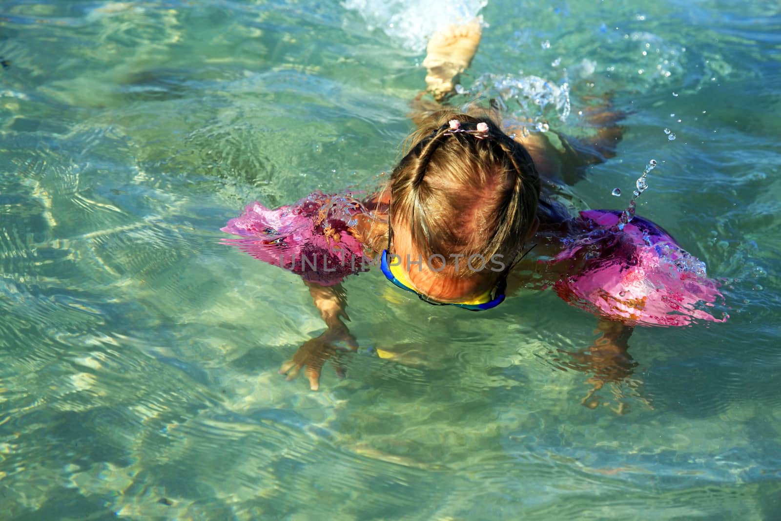 Little girl dives in the clear sea by friday