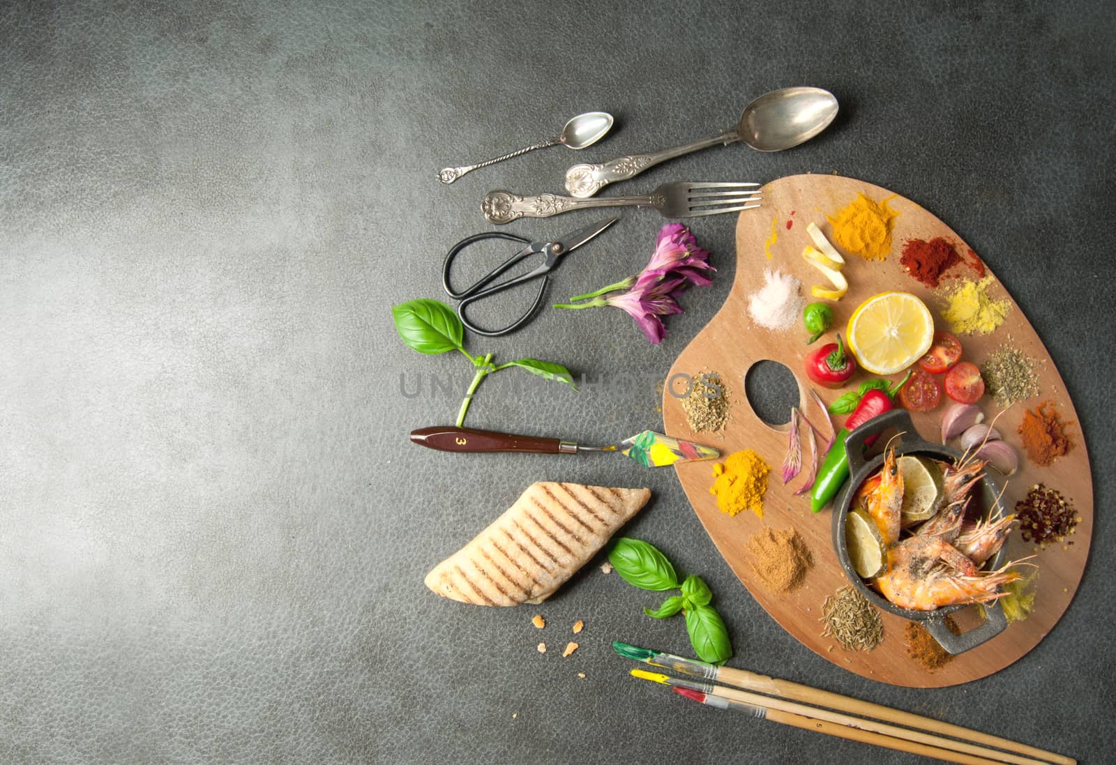 Fresh cooking ingredients including herb and spices on a painters palette with space