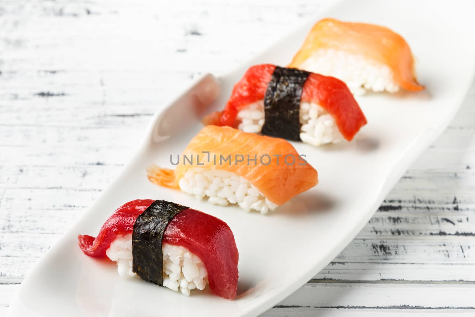 Set of salmon and red tuna Nigiris on white plate over old white wood. Raw fish in traditional Japanese sushi style. Horizontal image.