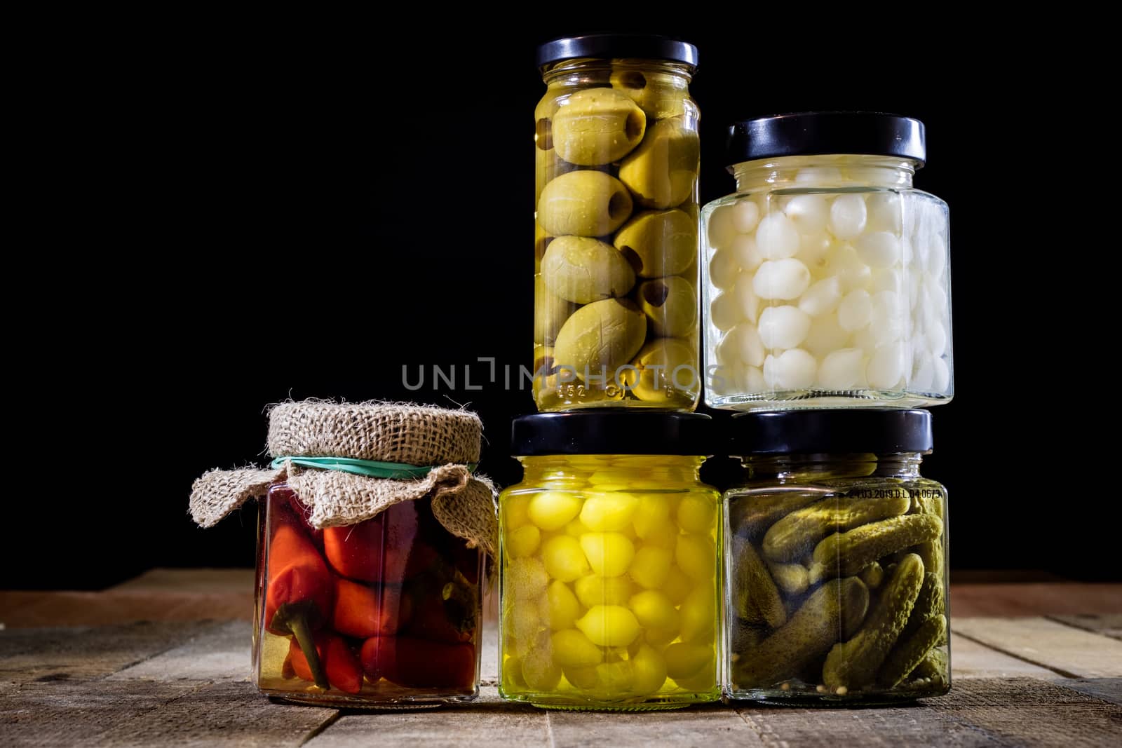 Mortar, vegetables in jars for the winter, wooden table in the old kitchen. Black background.