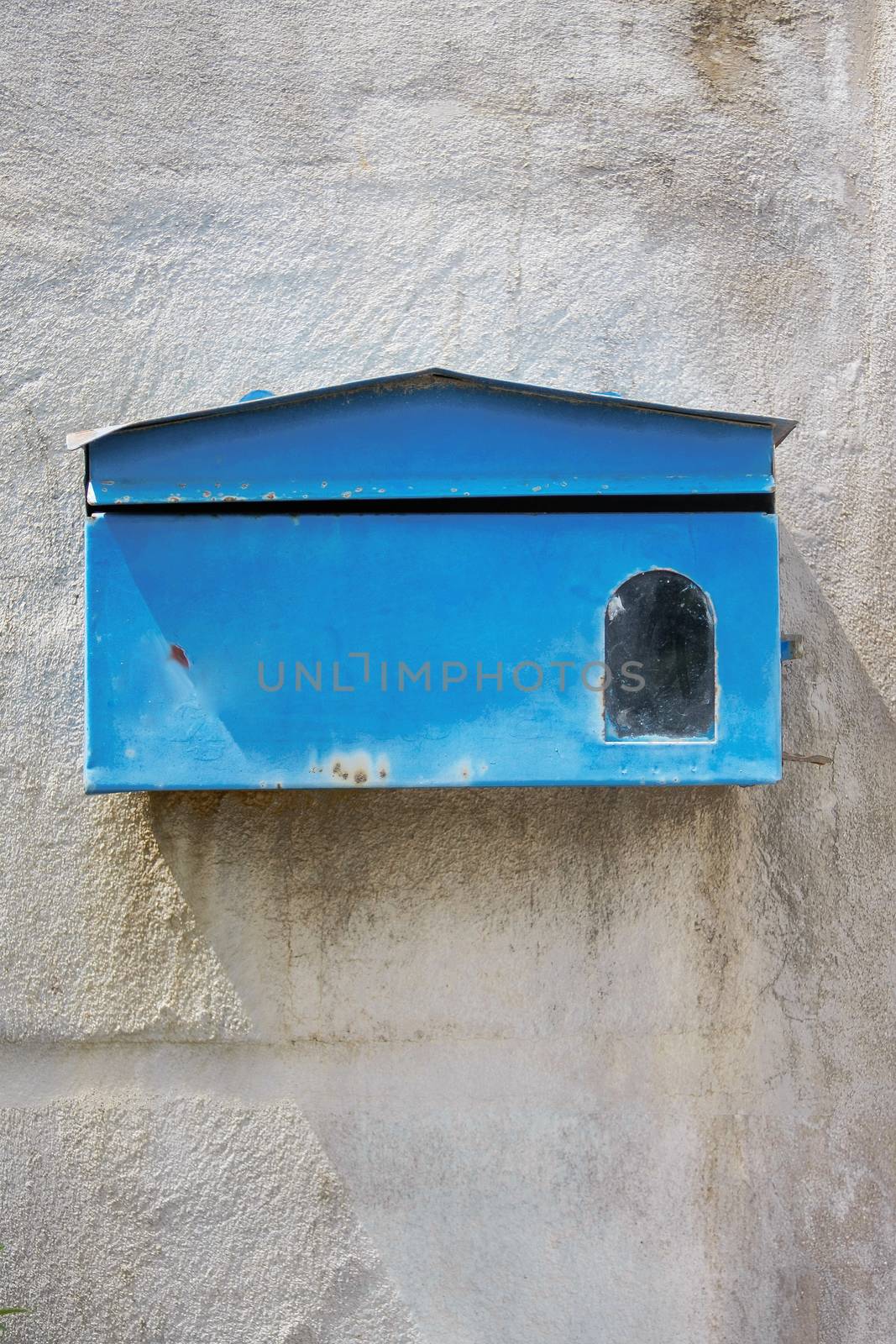 old blue mailbox on cement wall
