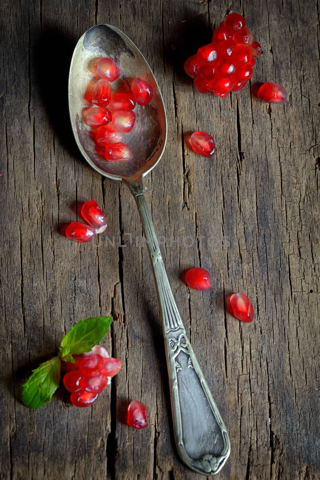 Ripe pomegranate and spoon on wooden table