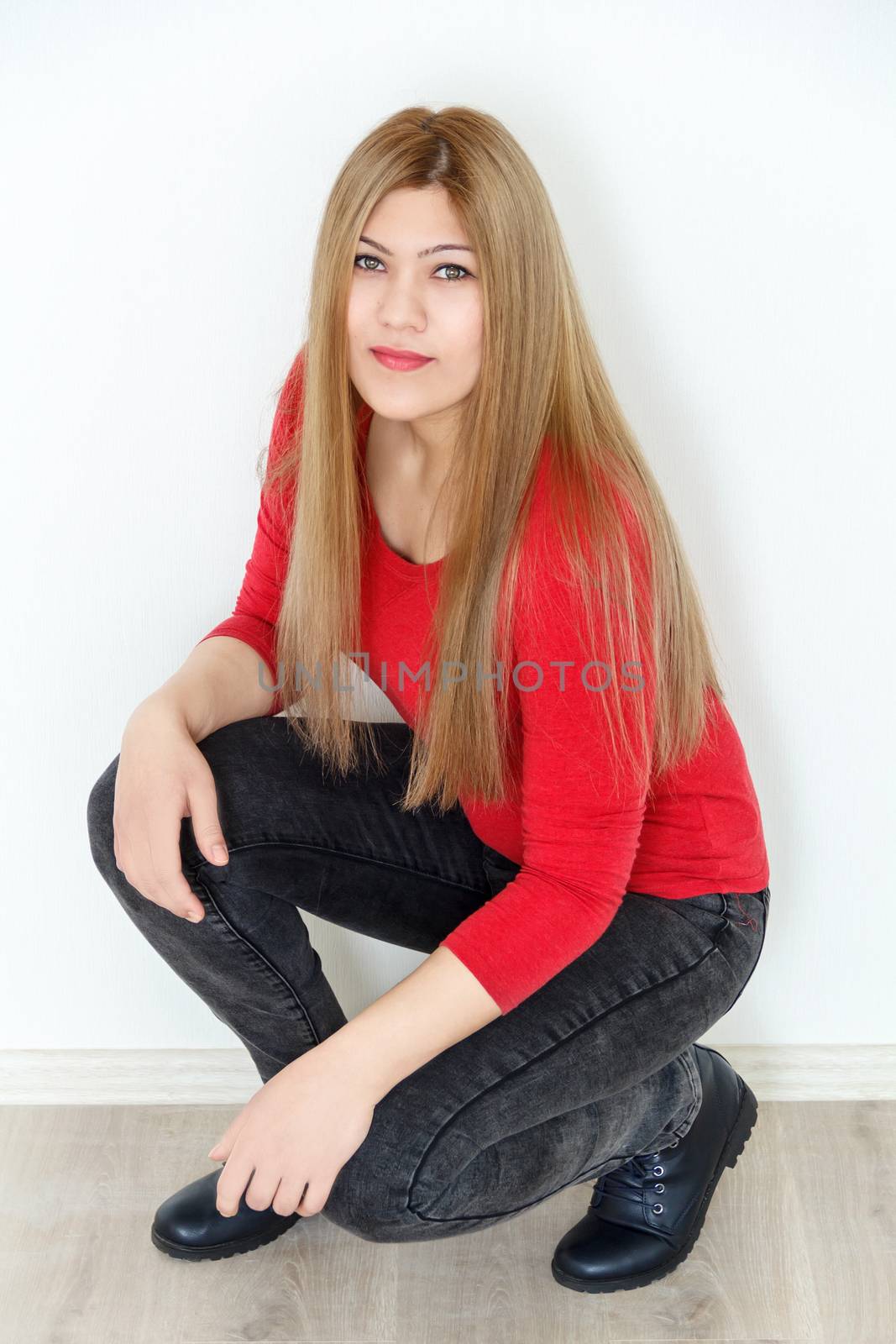 Vertical photo of girl is squatting with long brown healthy straight hair