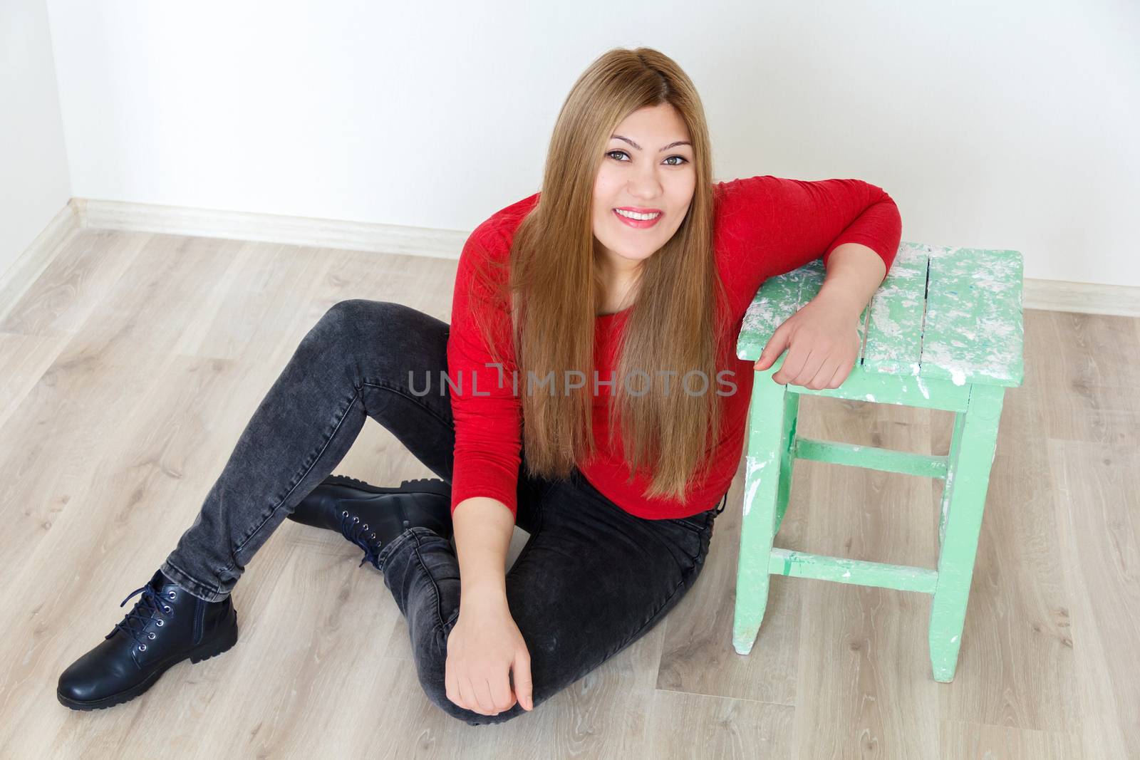 Horizontal attractive young girl with long brown healthy straight hair sitting on the floor