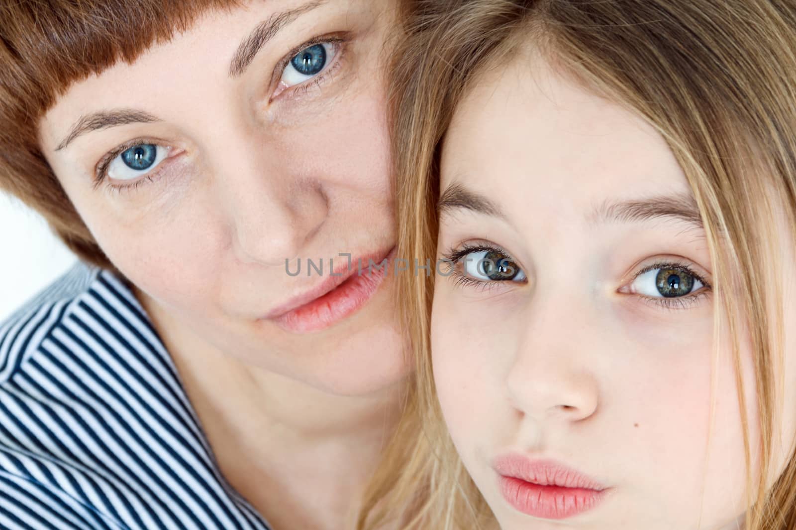 Portrait of happy mother and daughter near white wall