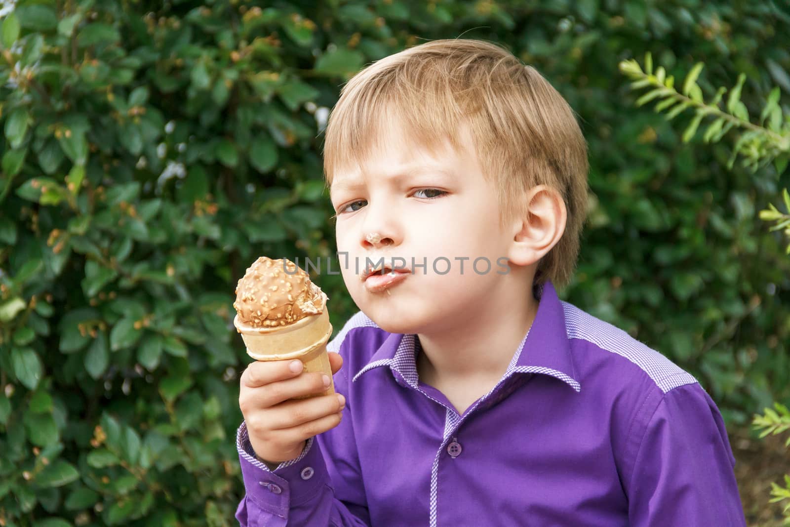 Blond boy are eating icecream with put out tongue by Julialine