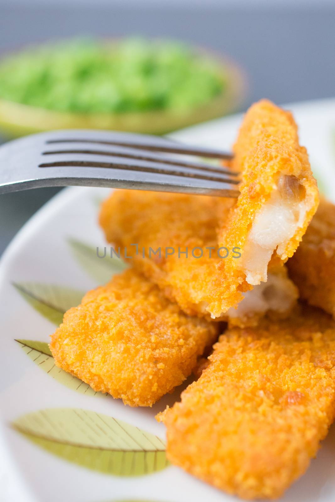 Breaded and Baked Fish Sticks, fingers  on a plate with a bowl of peas and a slice of lemon