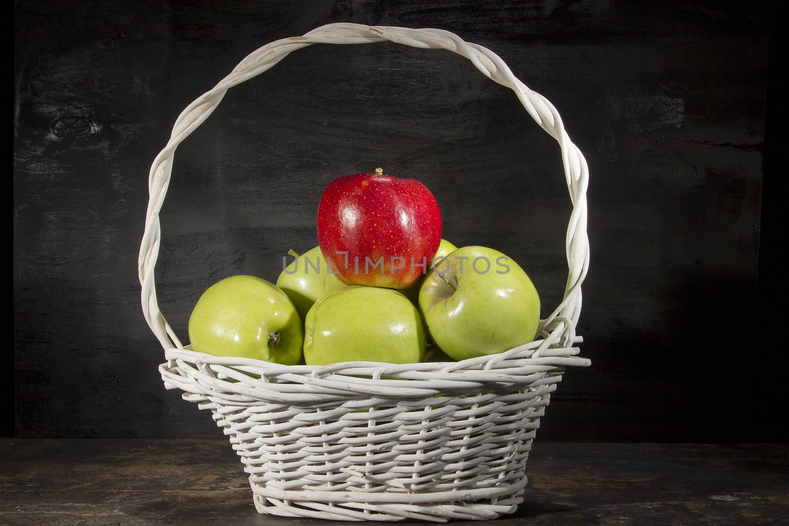 Ripe apples in a wicker basket on a black background