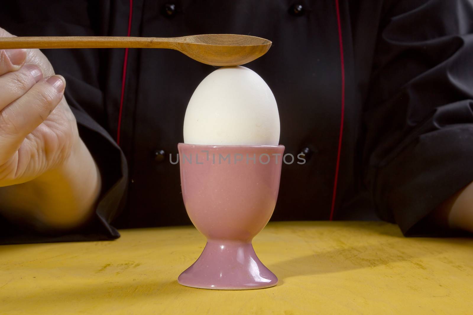 Boiled egg in the holder and the hands of the cook