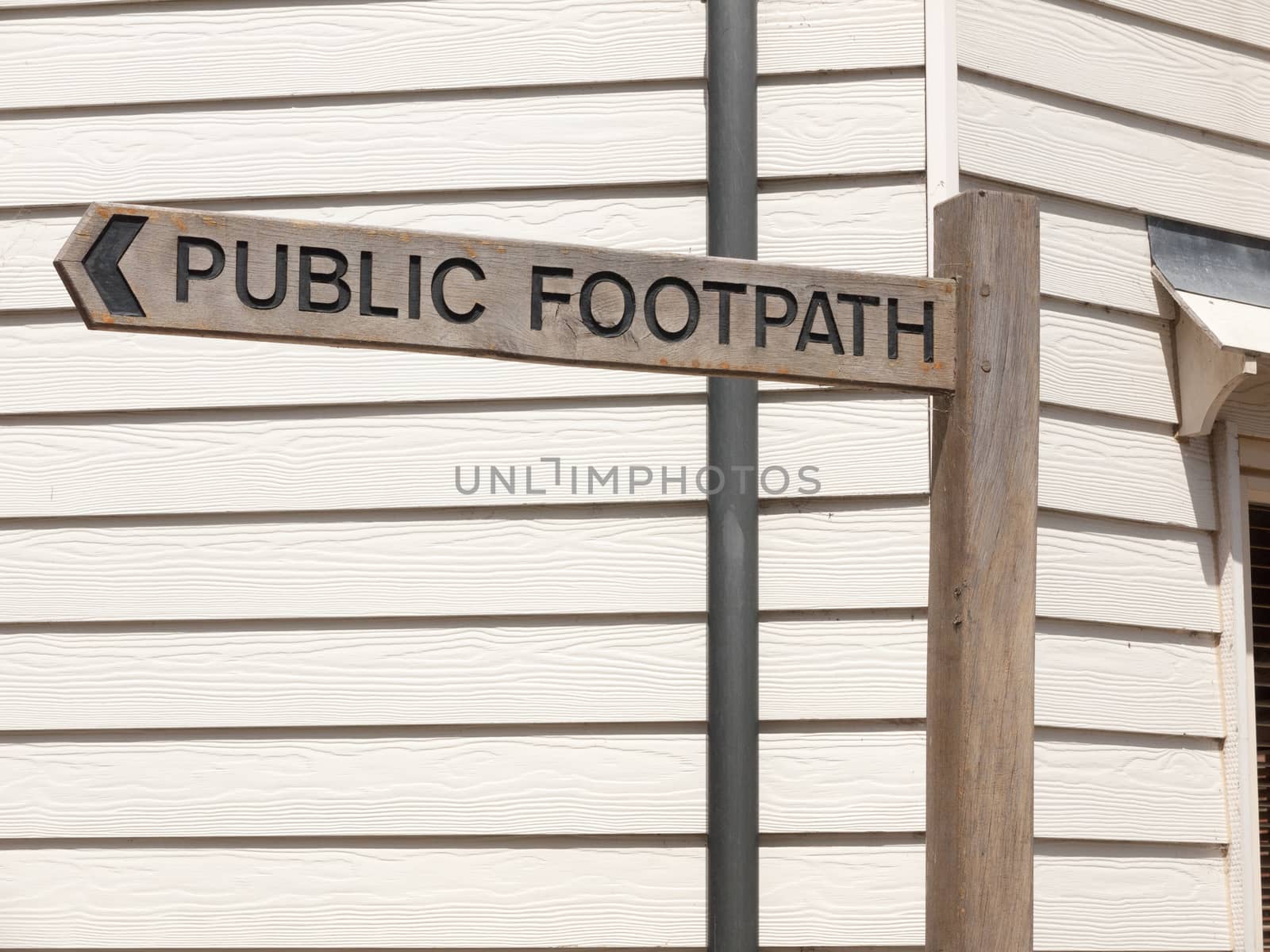 a clear wooden post sign in town saying public footpath