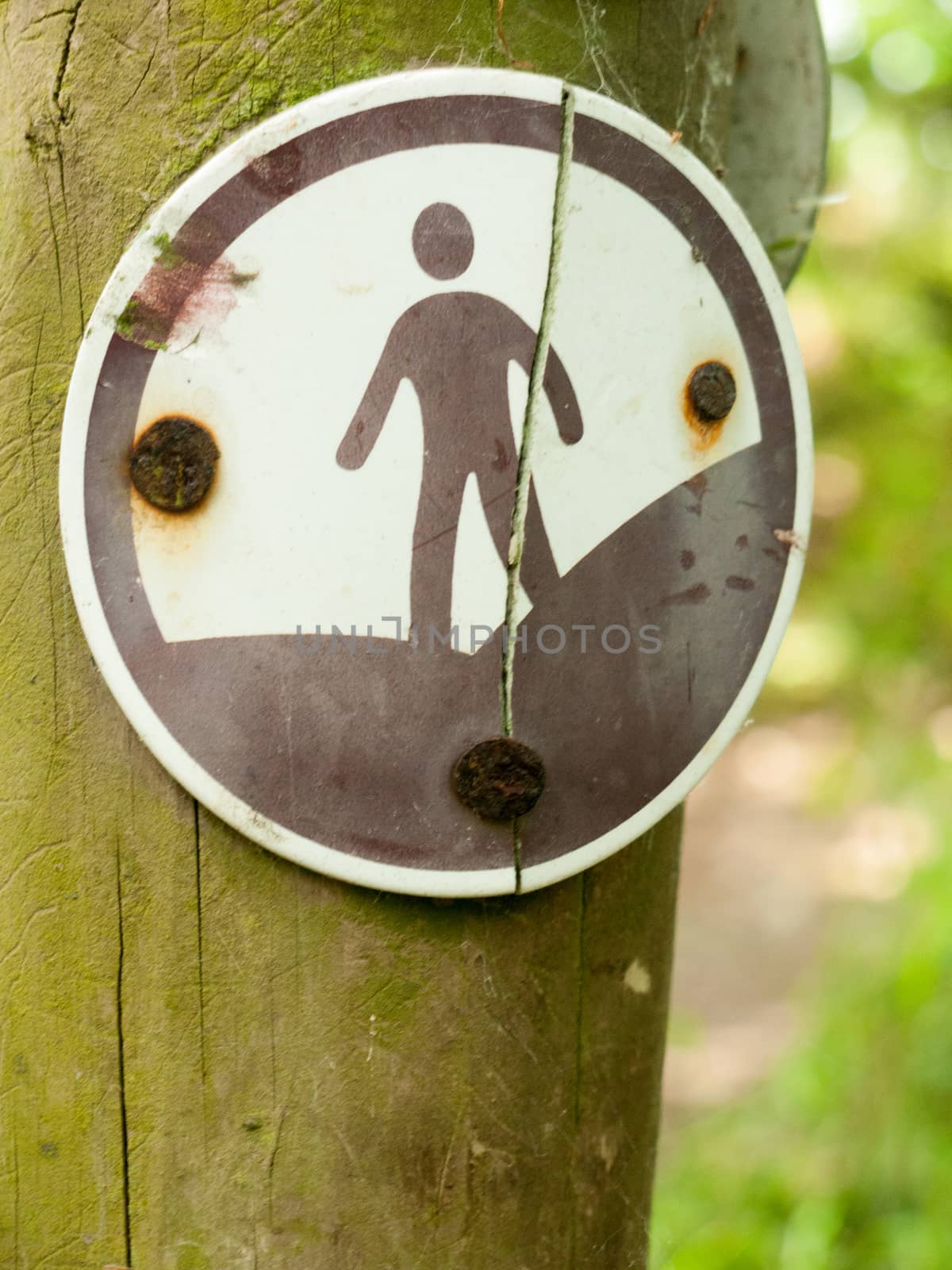 a rusty black and white sign with a man on it representing a country walking footpath