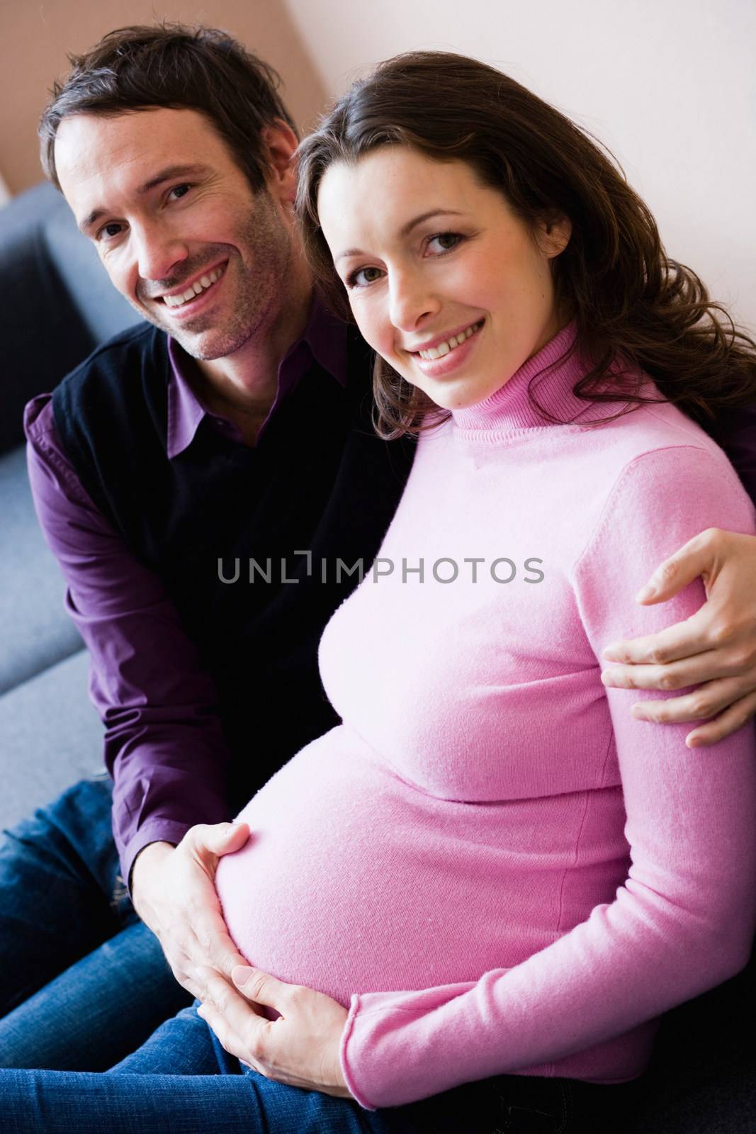 Pregnant woman and man sitting on couch