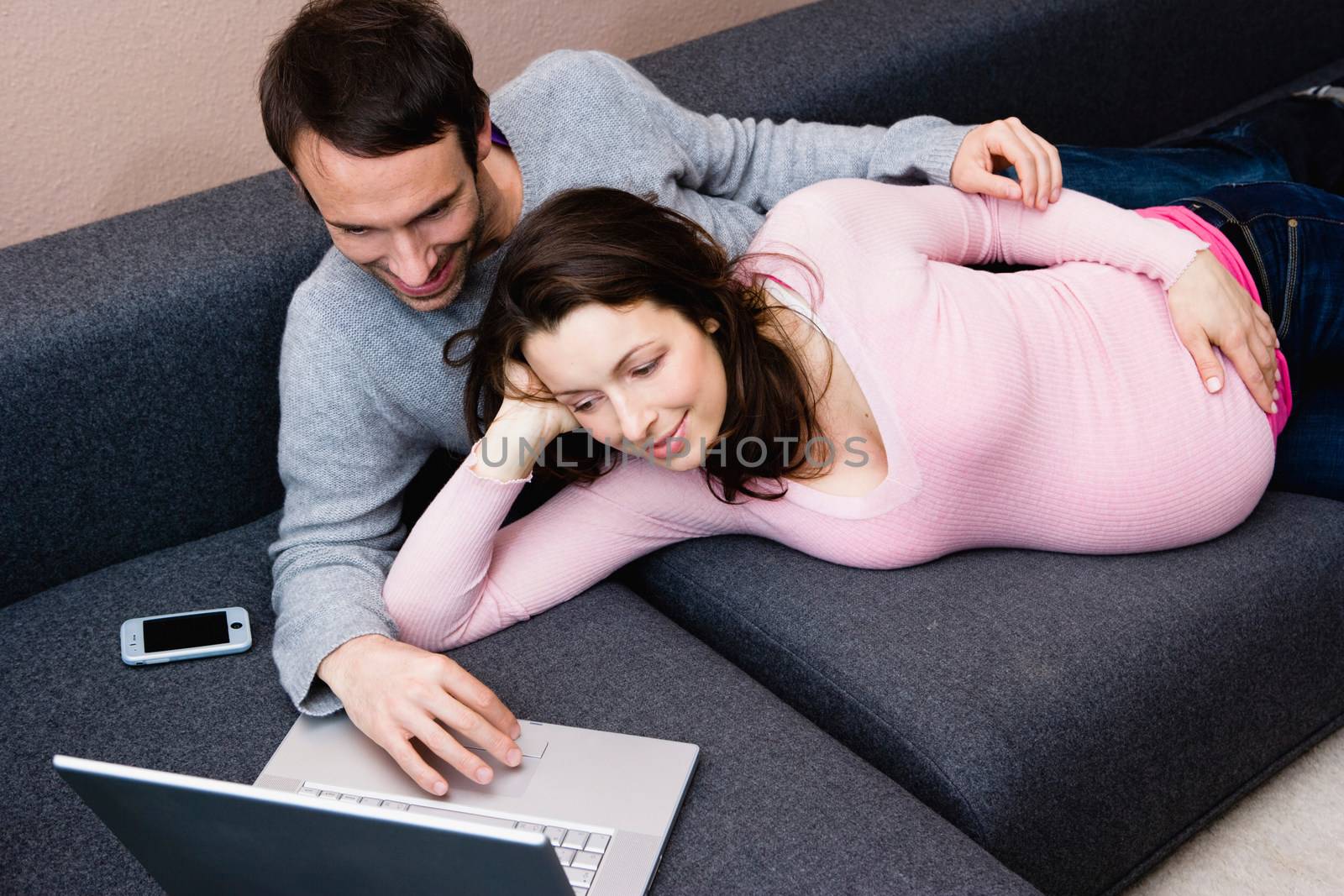 Pregnant woman and man laying on couch