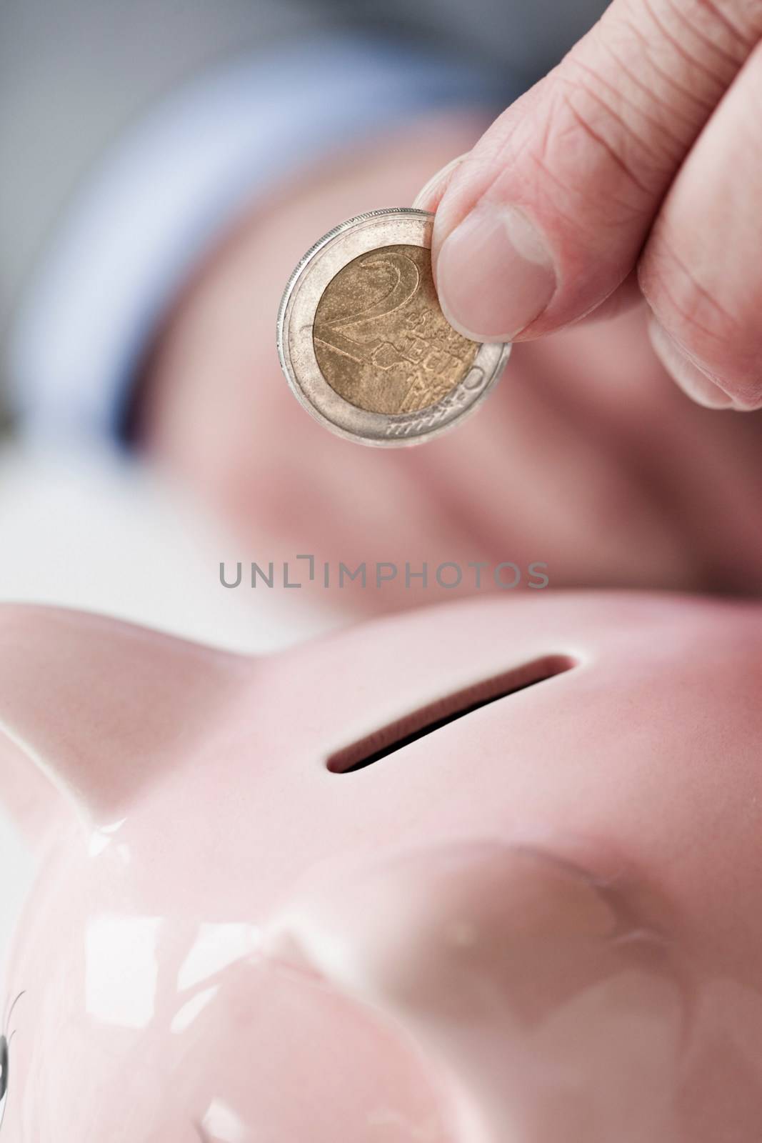 Hand putting coin into piggy bank