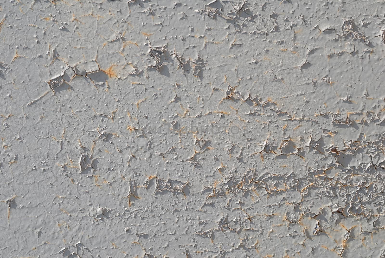 fragment of an iron surface is covered with grey color paint, which has long been under the influence of different climatic conditions