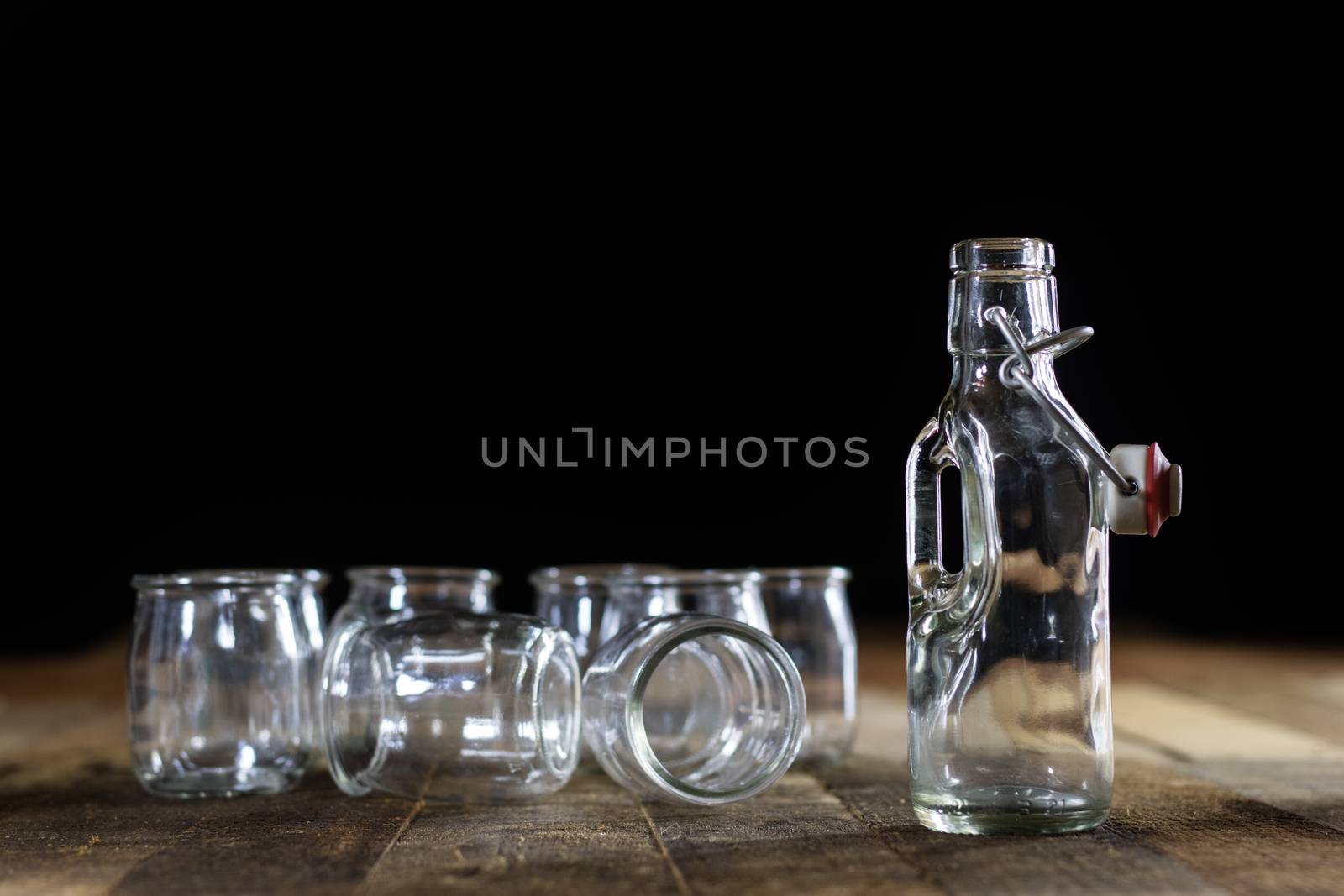 Glass empty containers on a wooden table. Jars, bottle. Black background