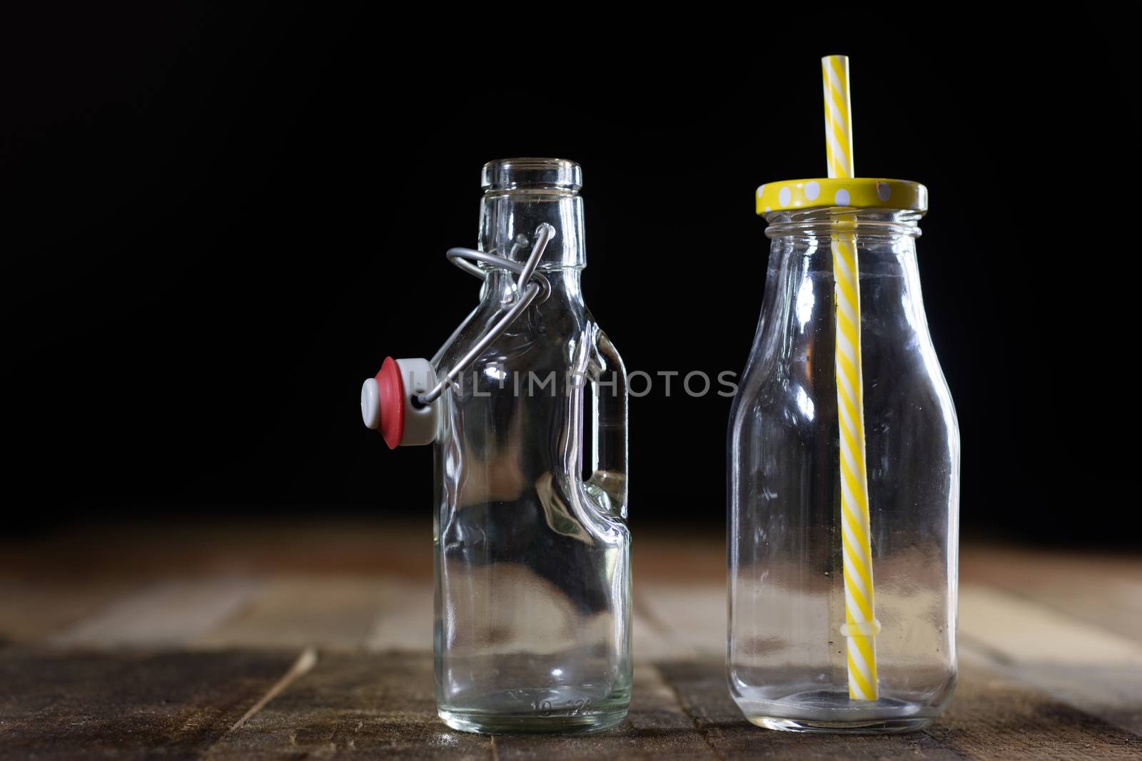 Glass empty containers on a wooden table. Jars, bottle. Black background