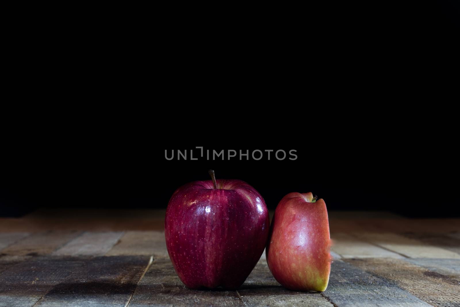 Red tasty wet apple on a wooden table. Black background.