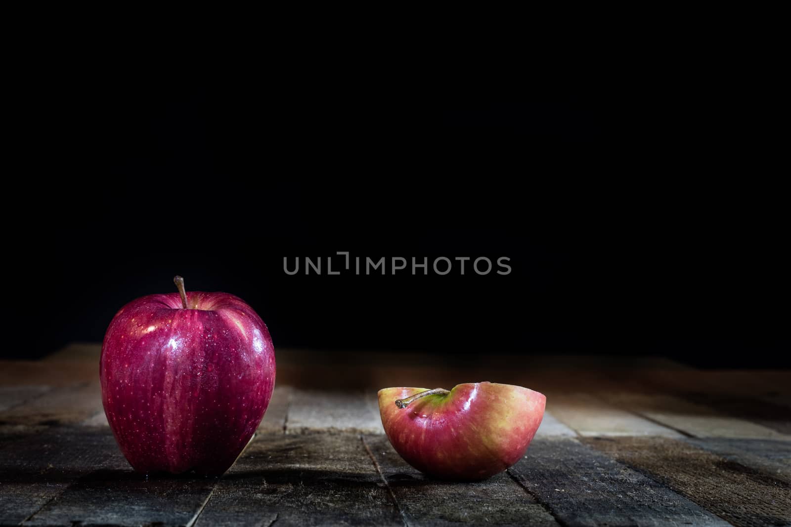 Red tasty wet apple on a wooden table. Black background.