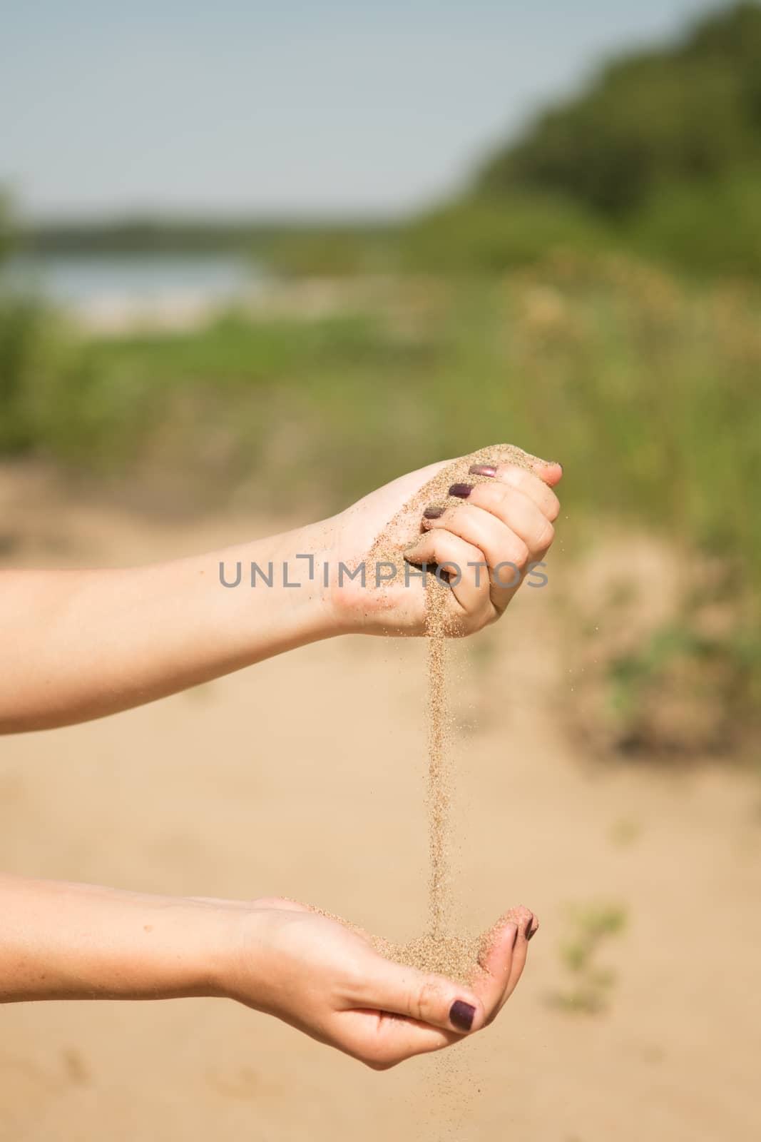 sand running through hands of woman in the beach