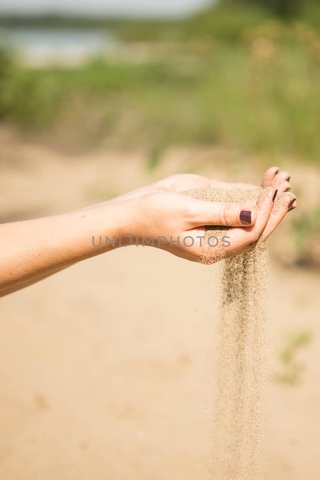 sand running through hands of woman in the beach