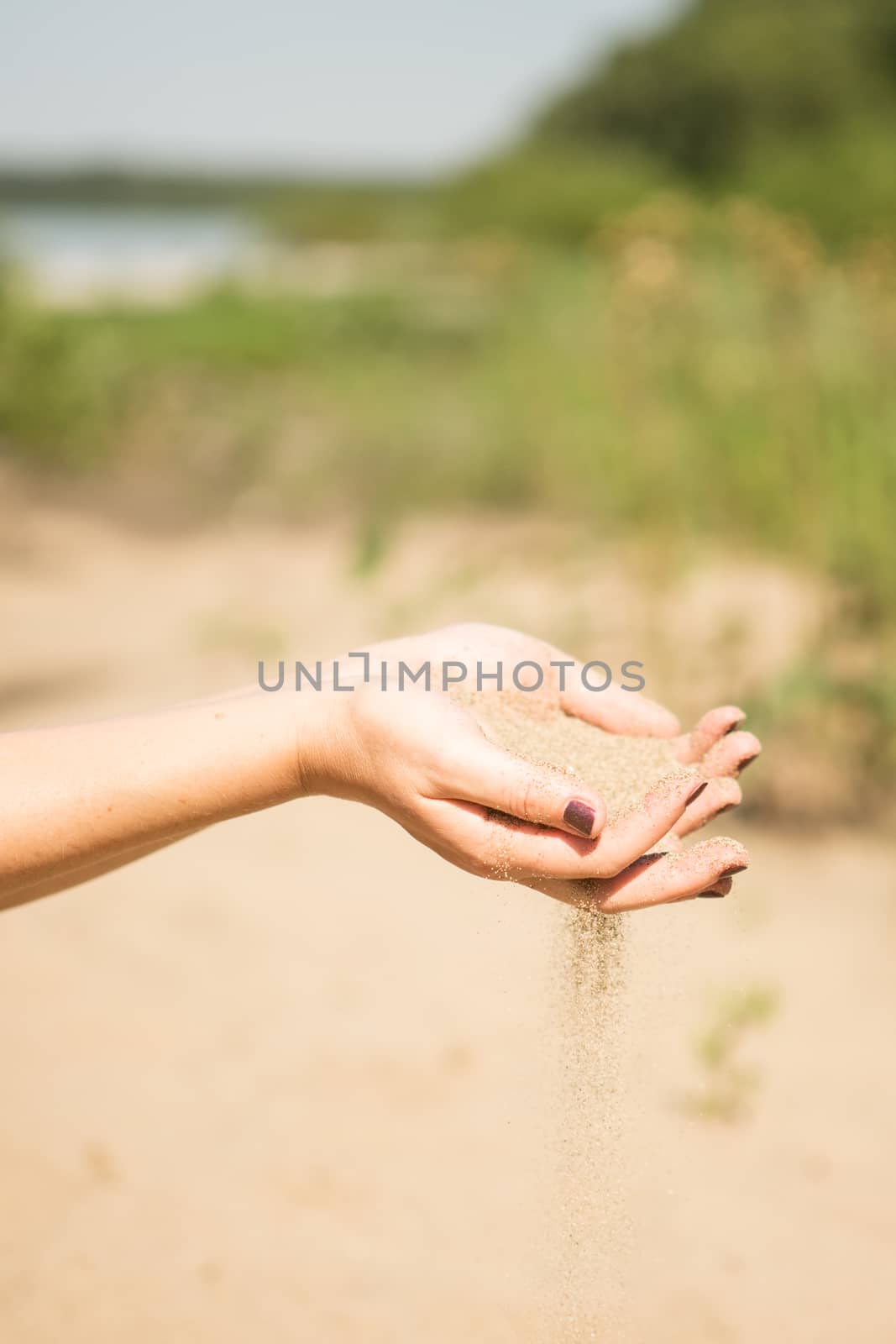 sand running through hands of woman in the beach