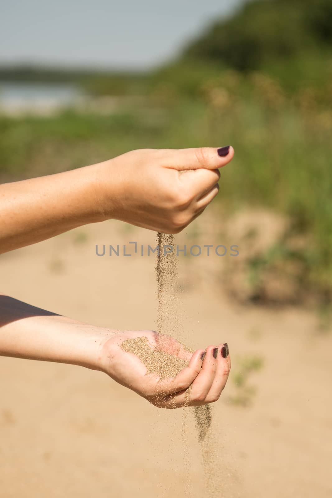 sand running through hands of woman in the beach