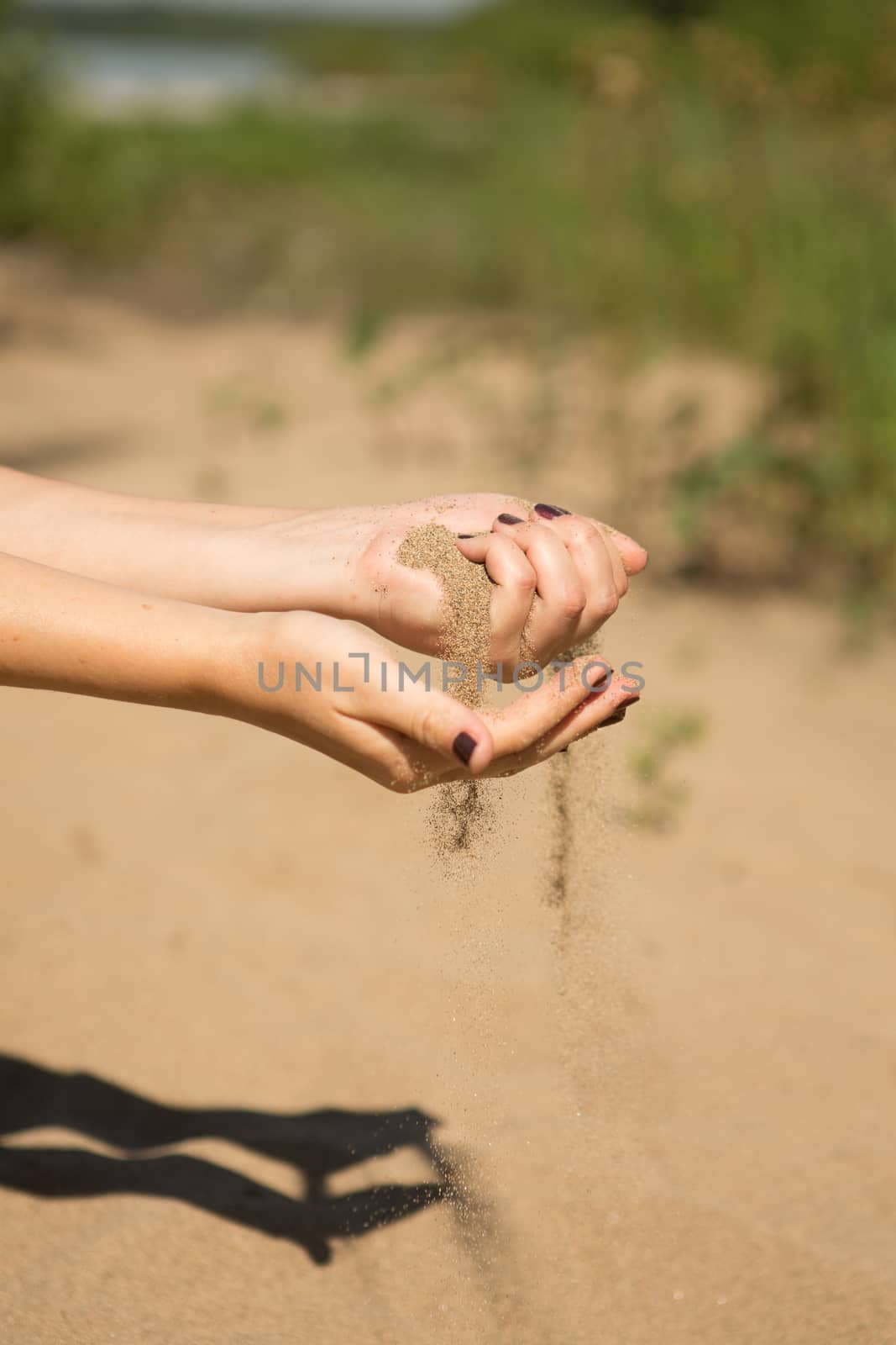 sand running through hands of woman in the beach