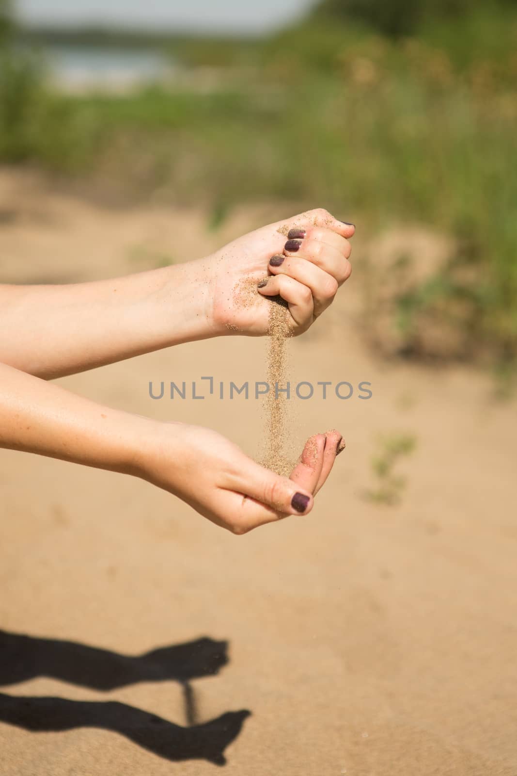 sand running through hands of woman in the beach