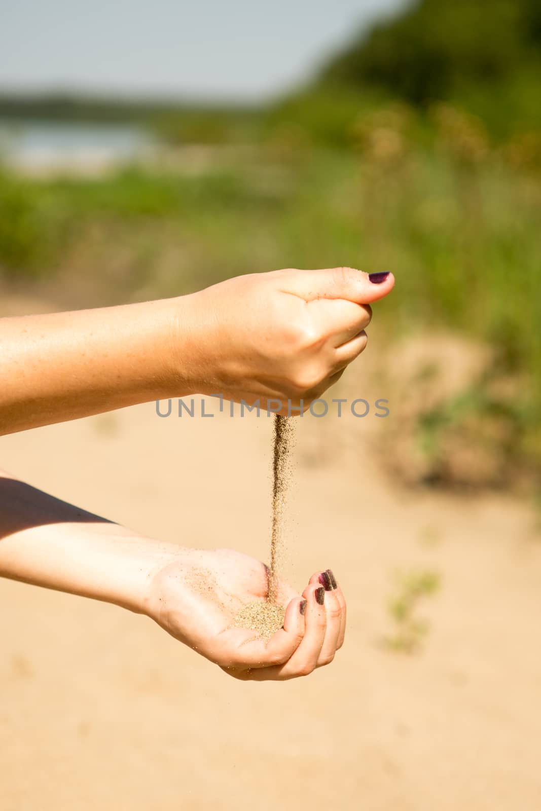 sand running through hands of woman in the beach