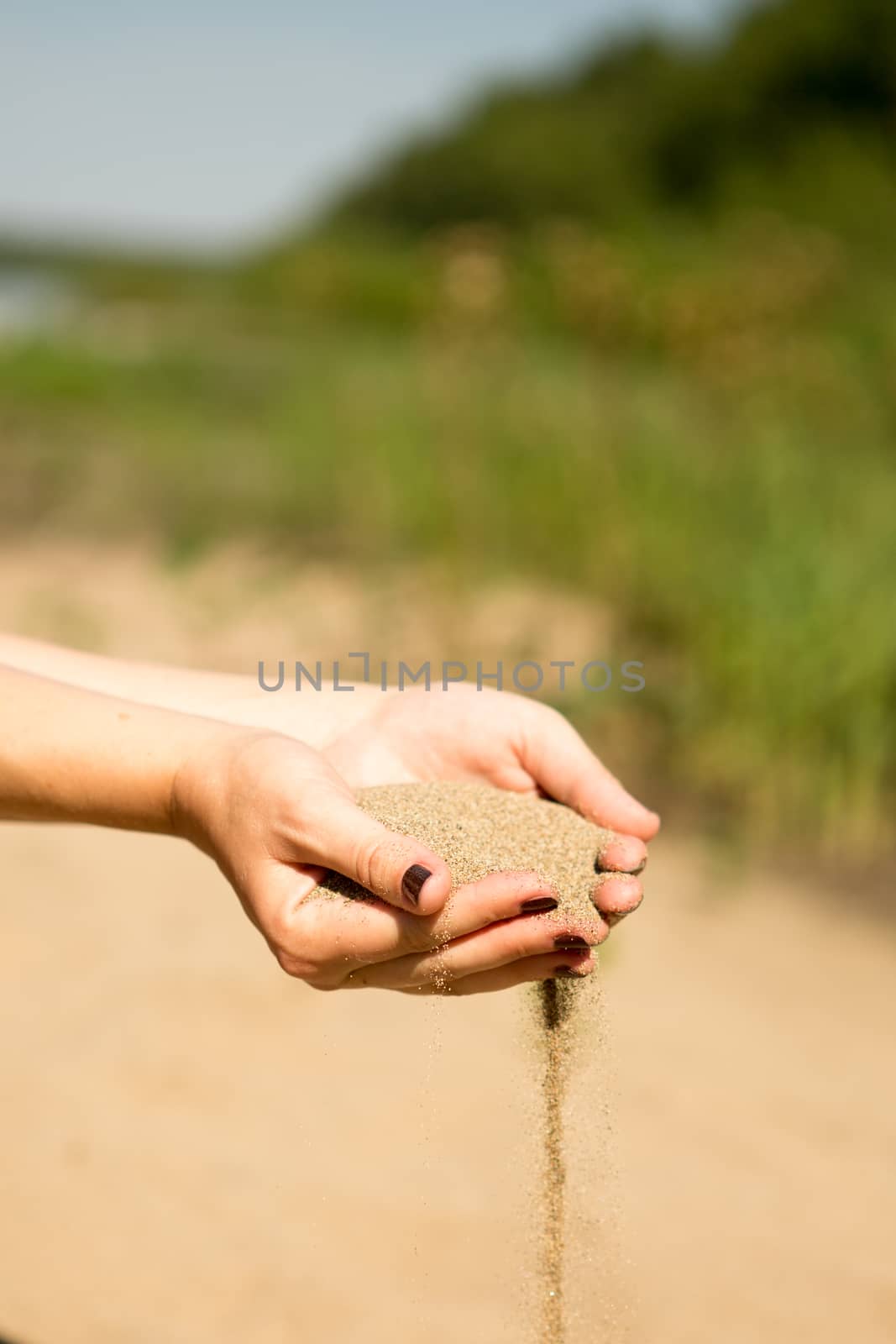 sand running through hands of woman in the beach