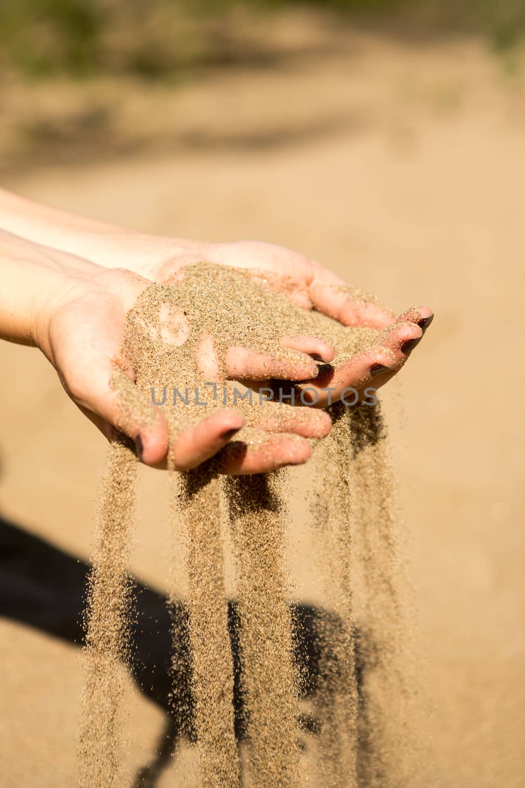 sand running through hands of woman in the beach