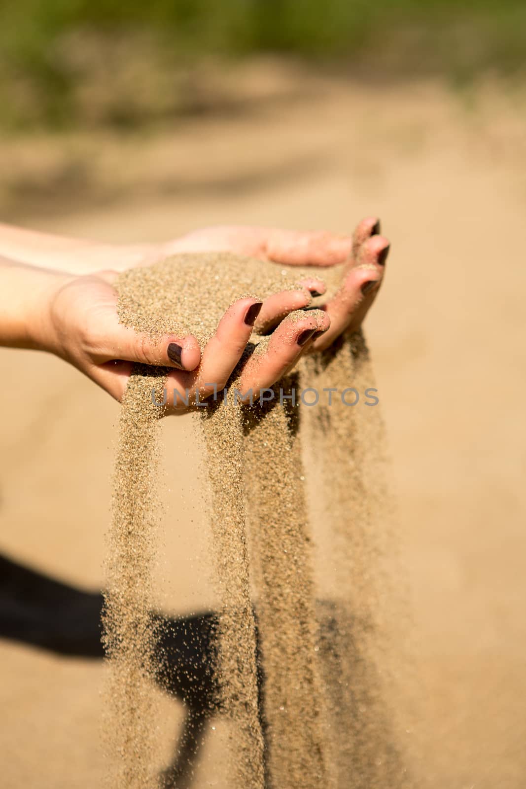 sand running through hands of woman in the beach
