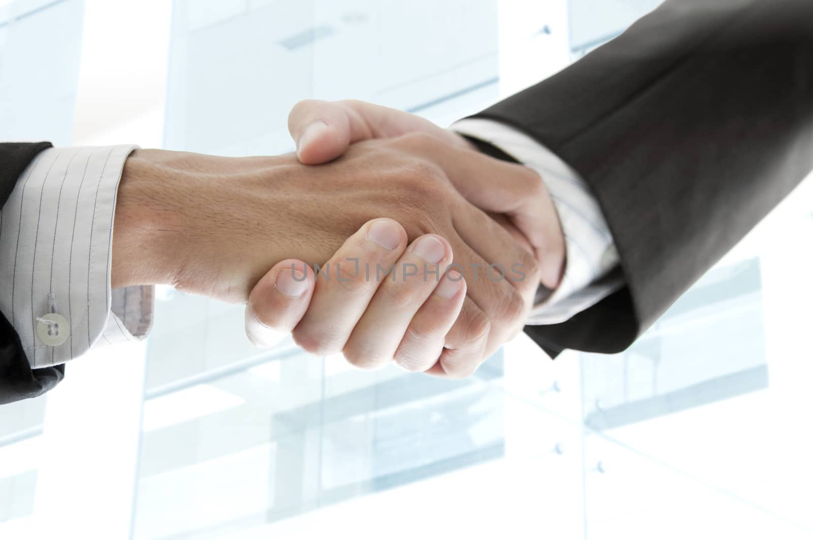 Close up businessmen handshake with modern skyscrapers as background.