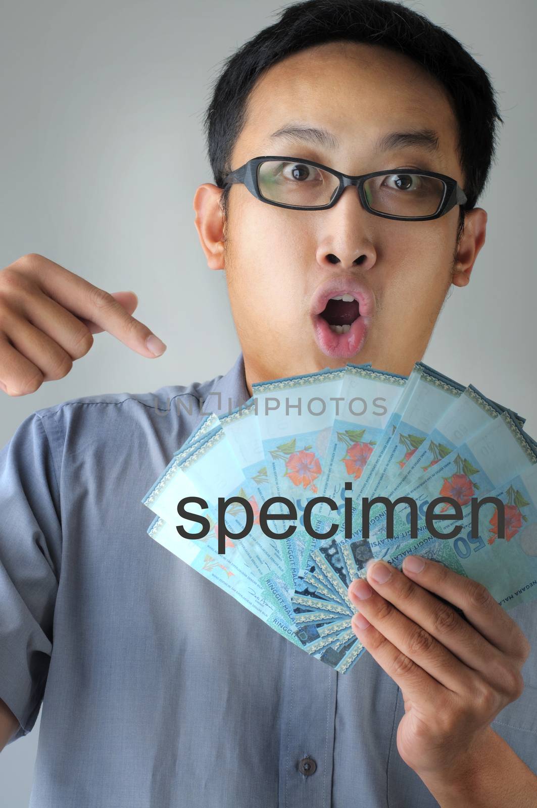 A Malaysian man pointing to money with surprising face