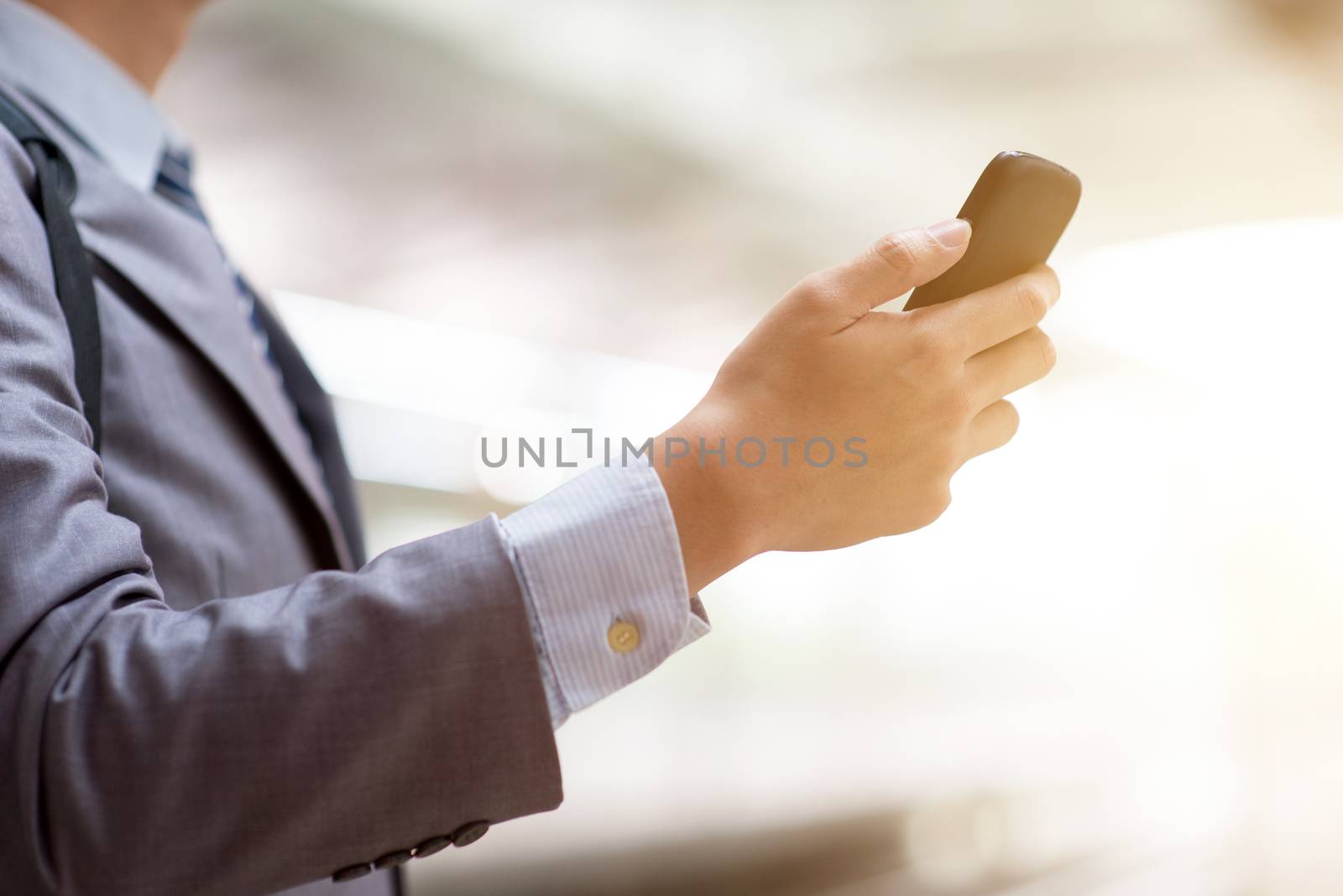 Business people hand using smart phone outdoors, bright sun flare background.
