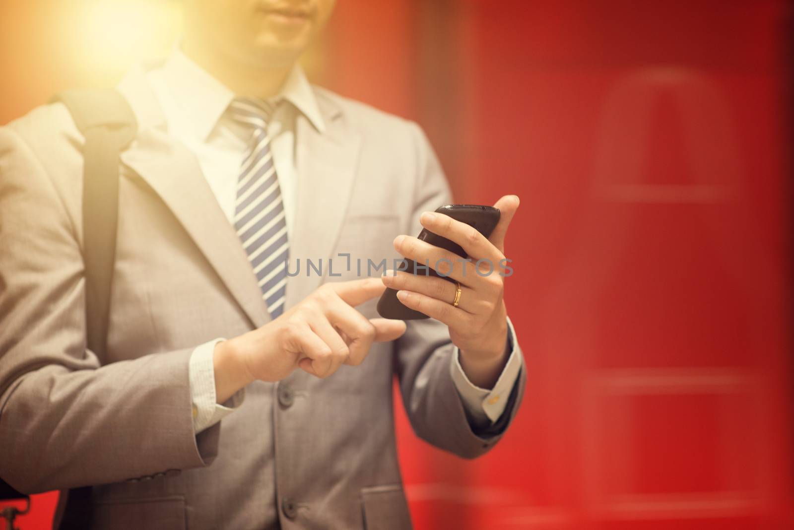 Business people hand using smartphone in subway station, train passing by at the background.