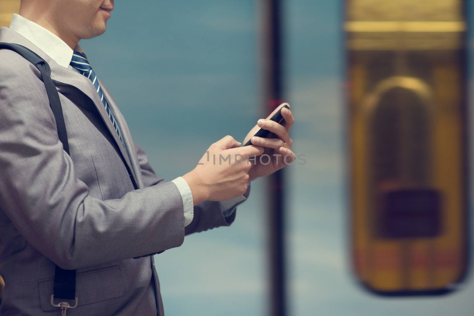 Business people hand using smart phone in subway station, train passing by at the background.