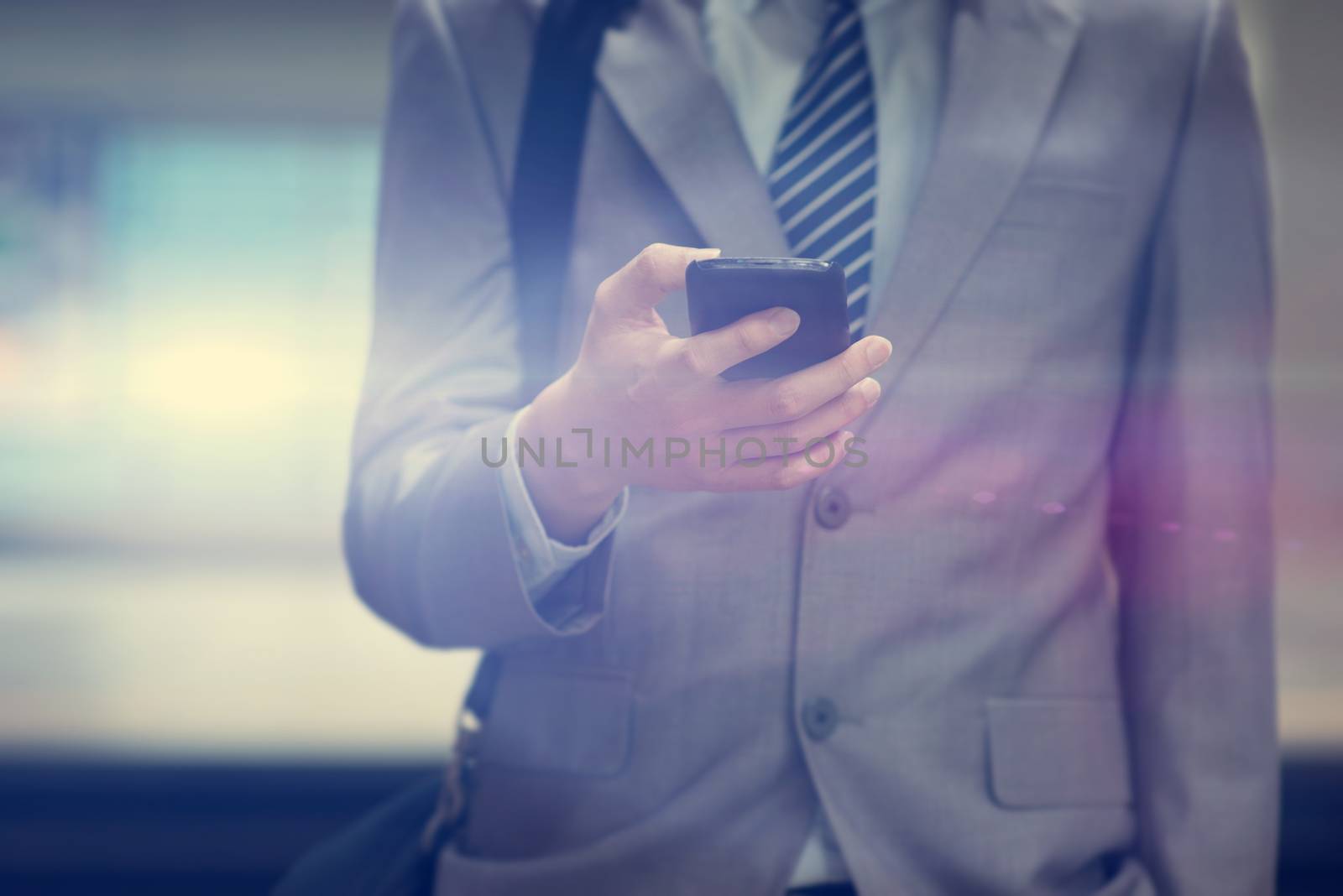 Business man hand using smart phone in subway station, train passing by at the background.