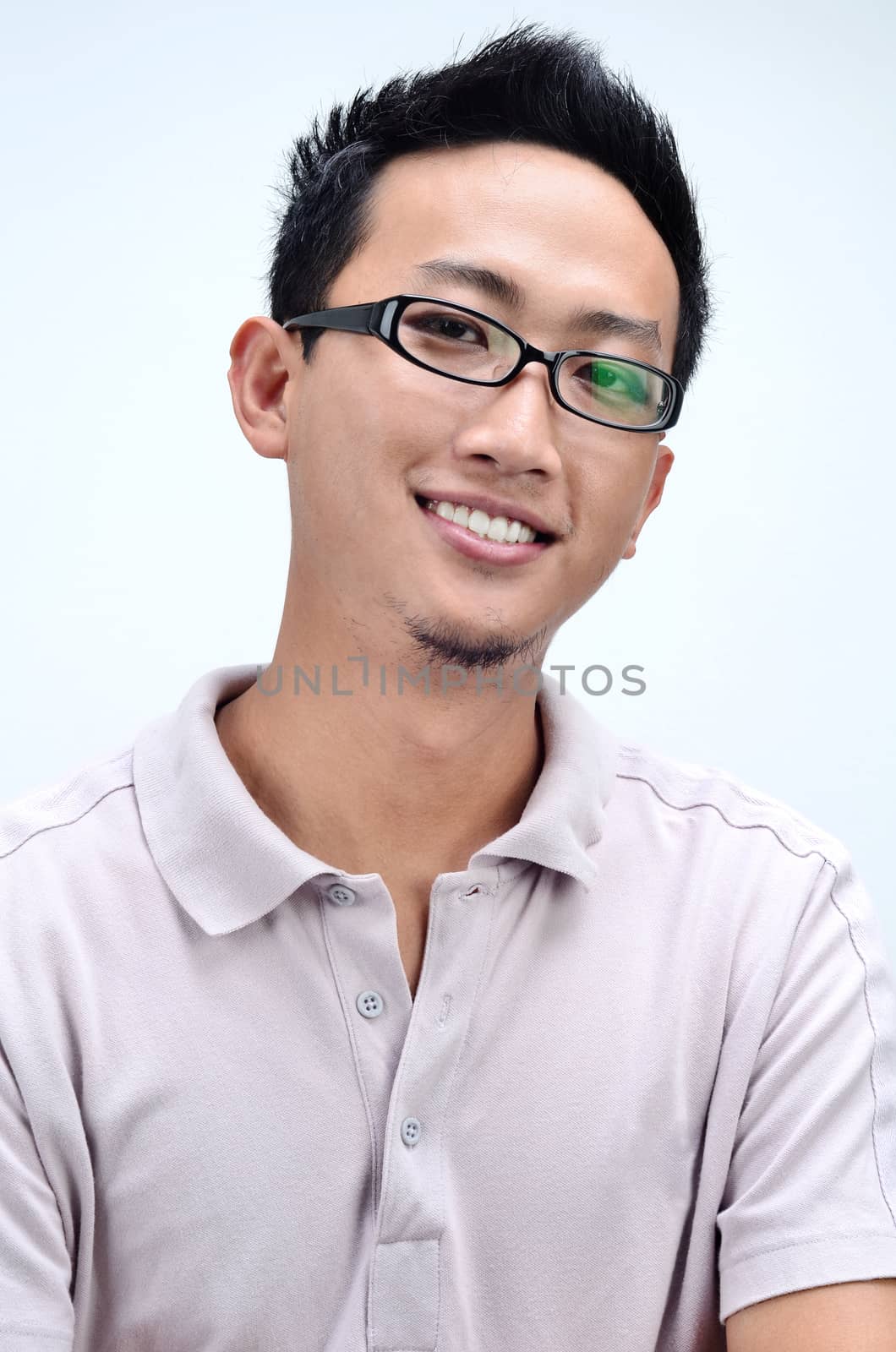 Young casual Asian male smiling, isolated on grey background.