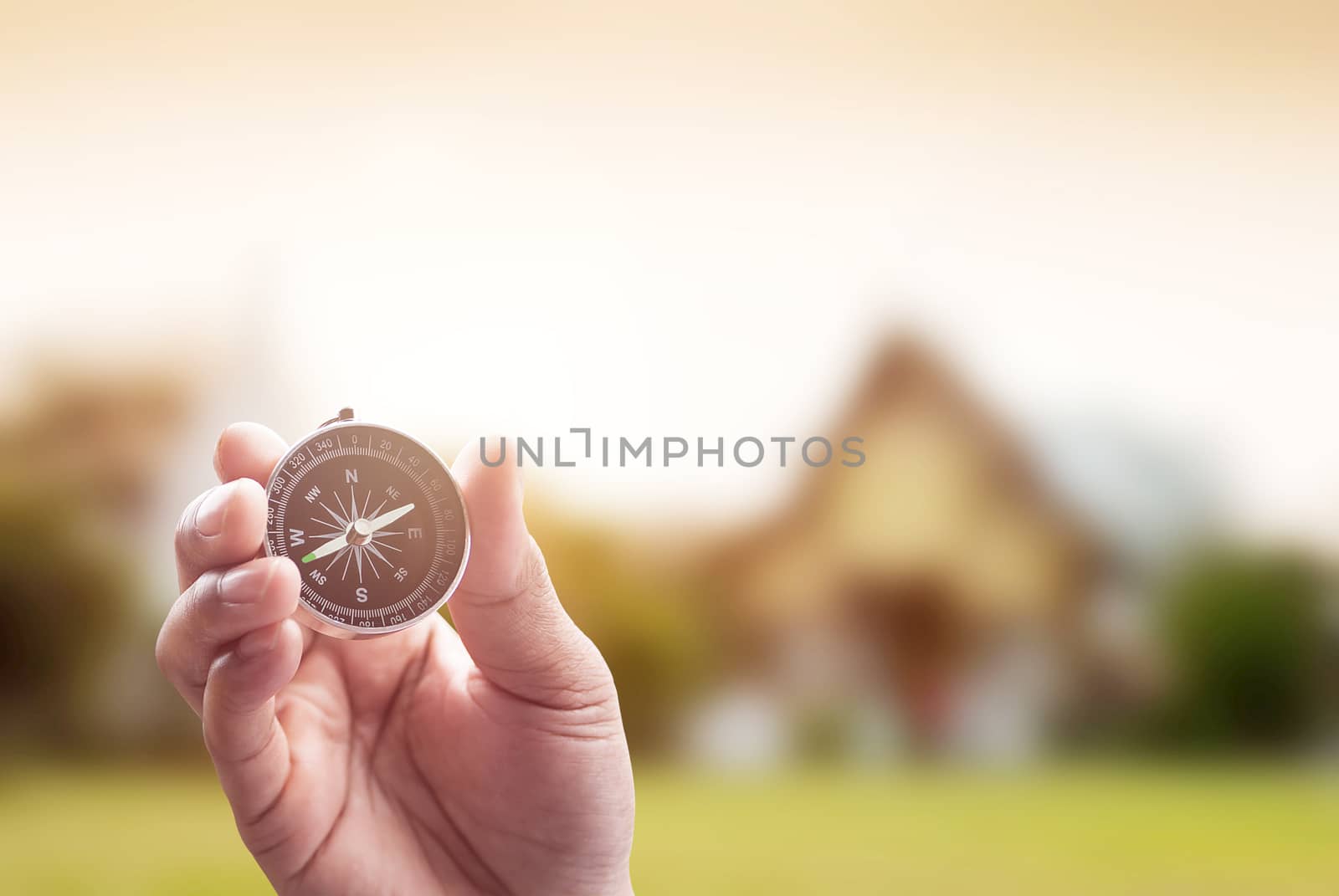 compass in hand on thai temple blur background with lighting flare