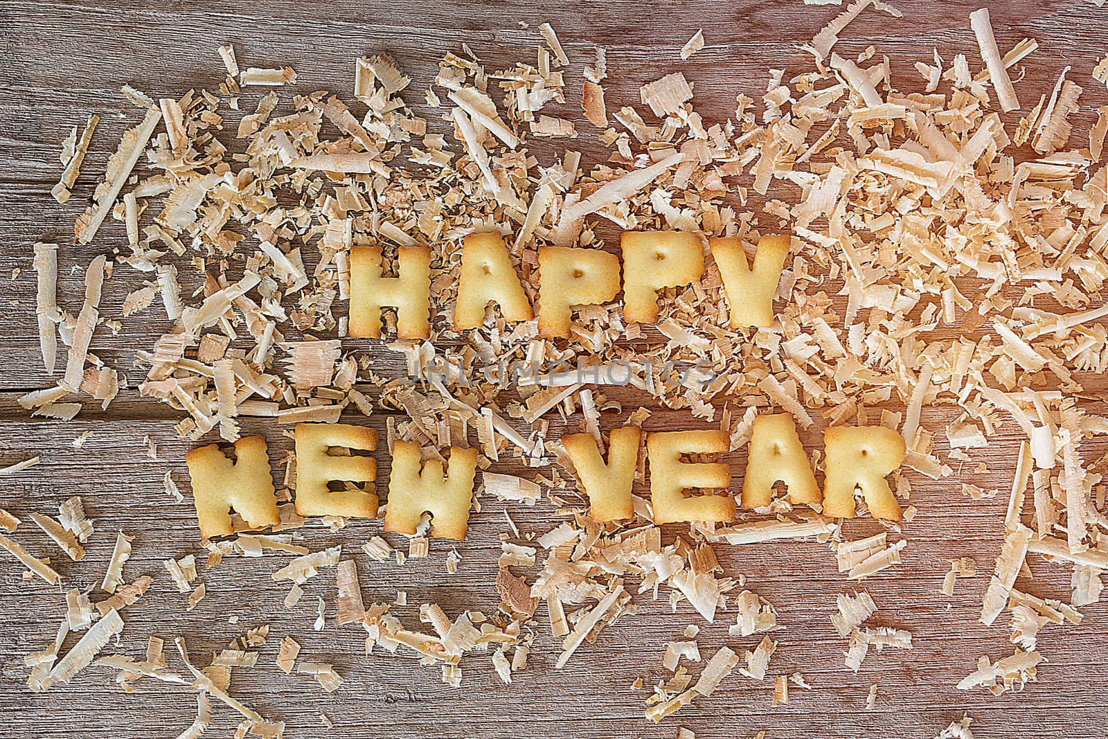 Happy new year text with bread and saw dust on wooden background