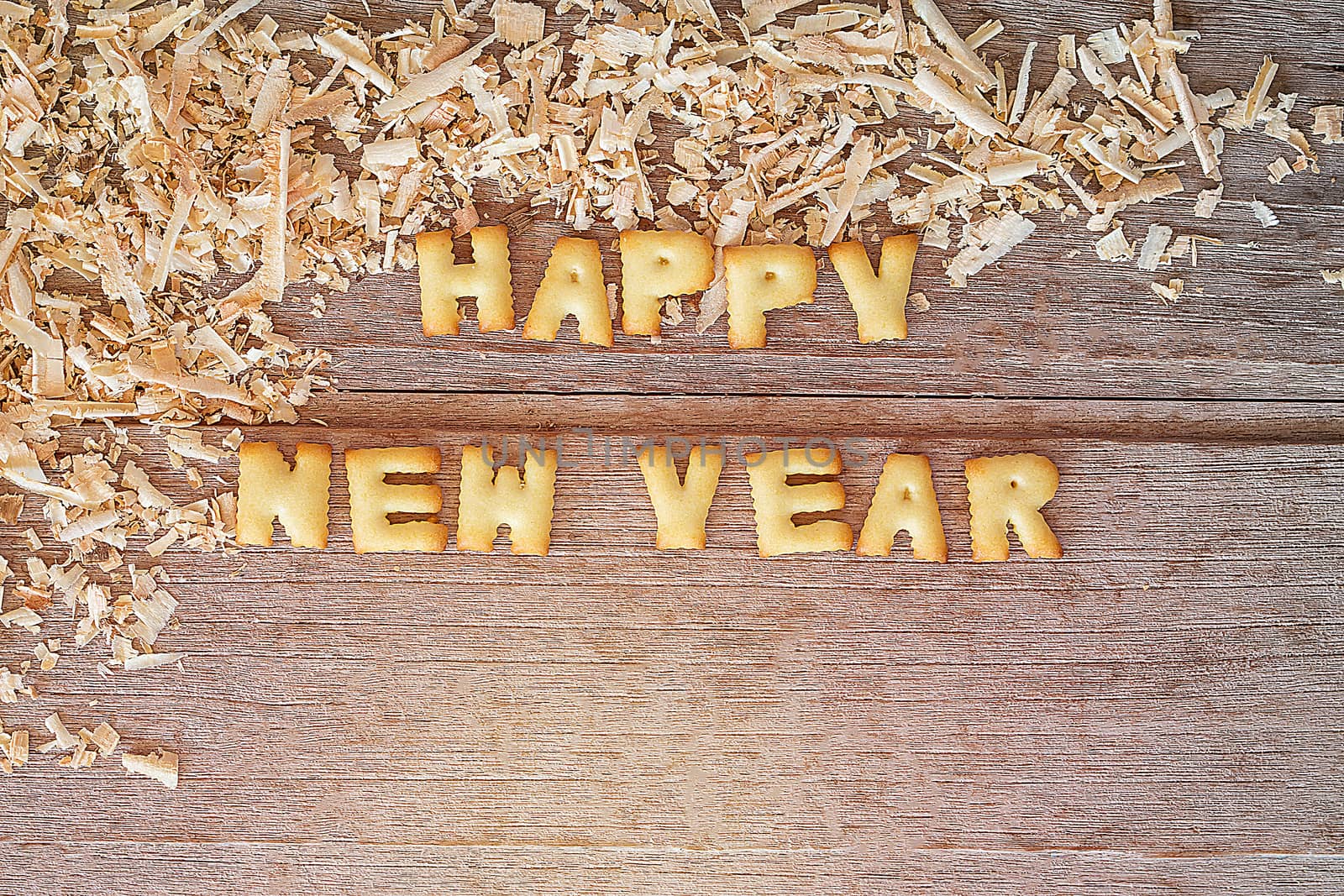 Happy new year text with bread and saw dust on wooden background