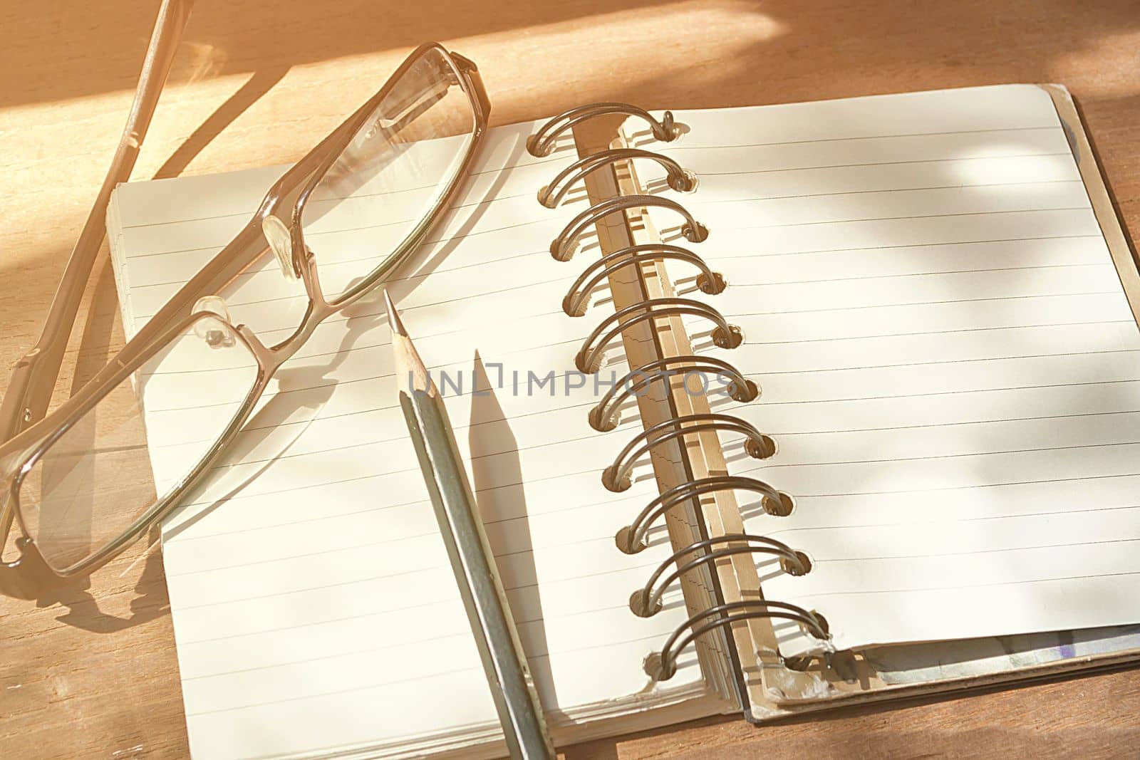 Empty page of notebook on desk, Black pencil and glasses on notebook, Space for text, Vintage style