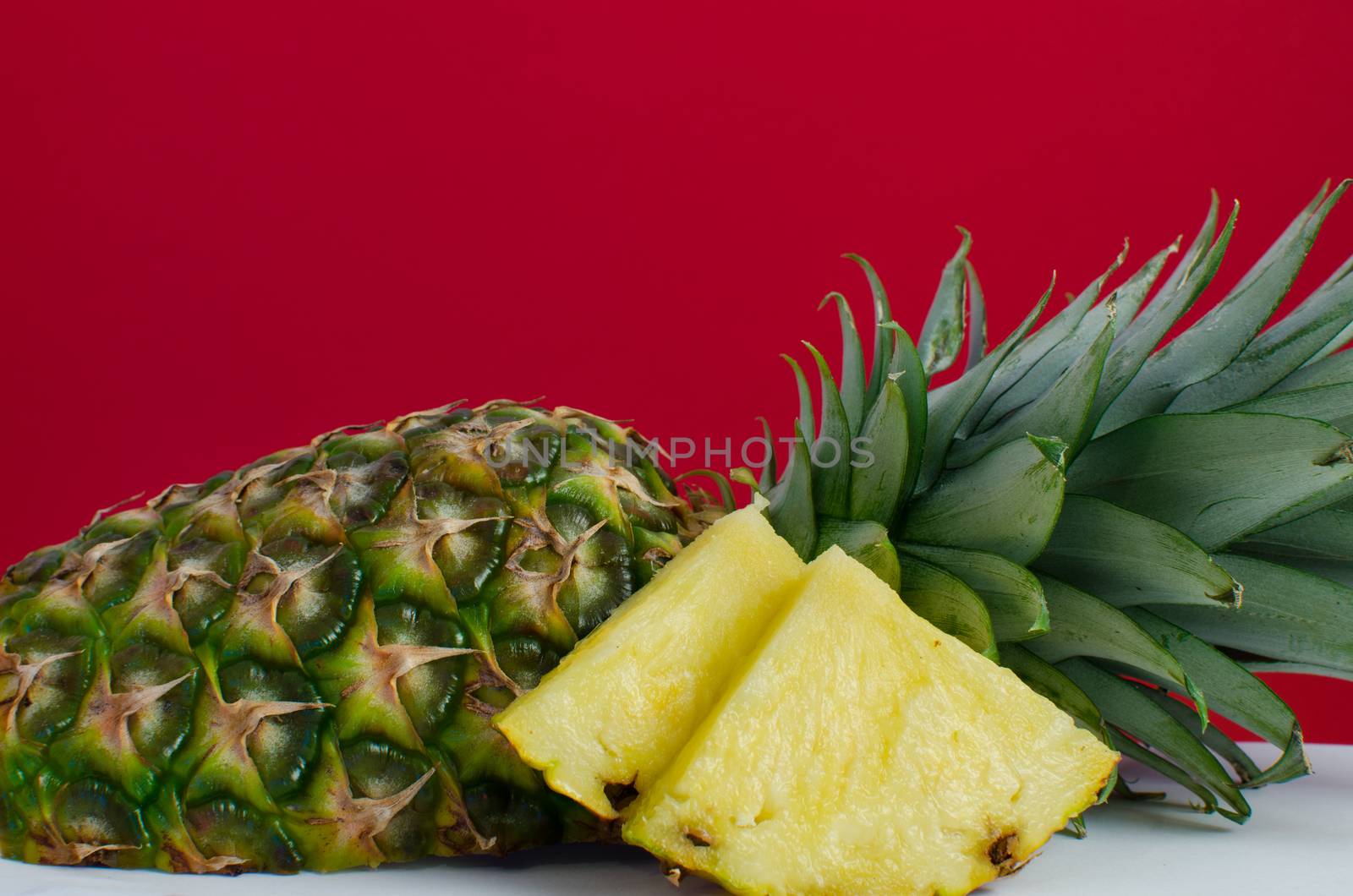 sliced pineapple fruit on red background, horizontal